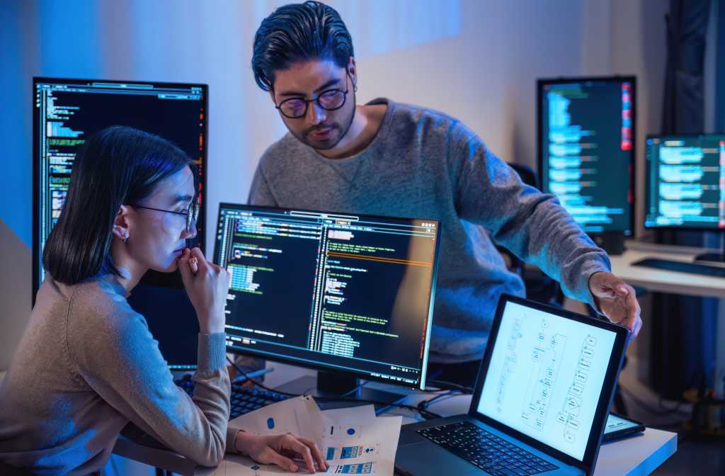 asian and Indian Developer  devops team discussion  about coding program with software computer at night in office